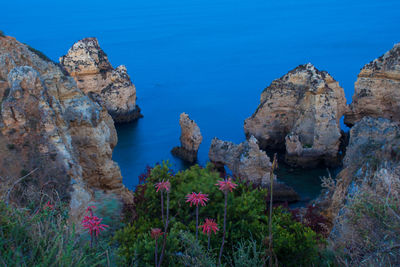 Rock formations by sea against blue sky