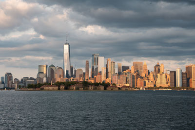 City at waterfront against cloudy sky