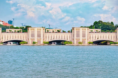 Arch bridge over river against cloudy sky