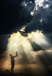 Rear view of man standing on field against sky during sunset