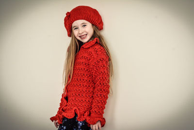 Portrait of smiling girl in warm clothing standing against white background