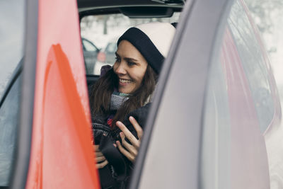 Smiling young woman looking through car window