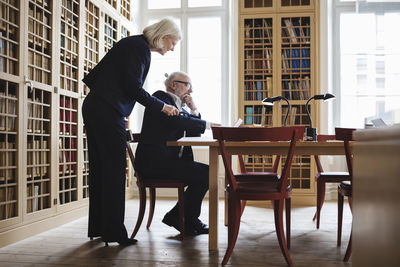 Side view of senior male and female lawyer discussing at table in library