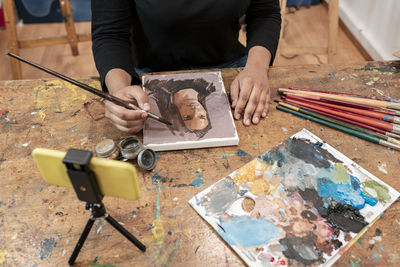 Young female artist painting on canvas at art studio