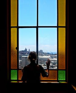 Rear view of woman looking through window