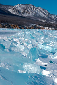 Pieces of crystal clear lake ice with mountains in background