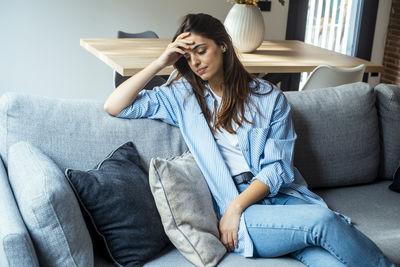 Young woman sitting on sofa at home