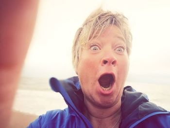 Close-up portrait of shocked woman standing at beach