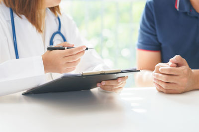 Midsection of woman holding smart phone on table