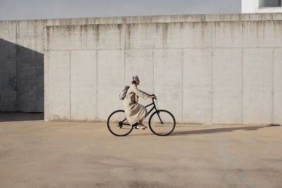 Man riding bicycle parked in front of wall