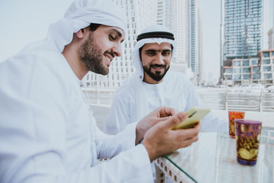 Smiling business people having discussion while sitting at cafe