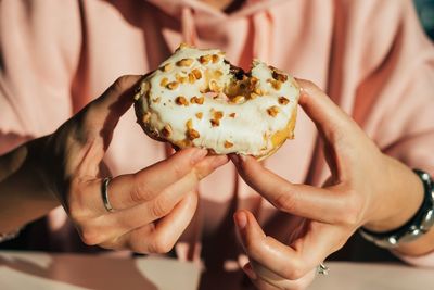 Midsection of woman having donut at table