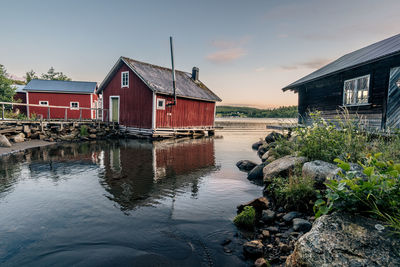 House by lake against sky