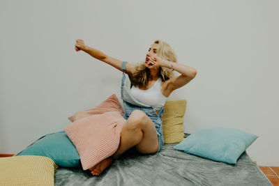 Happy young woman sitting on bed at home