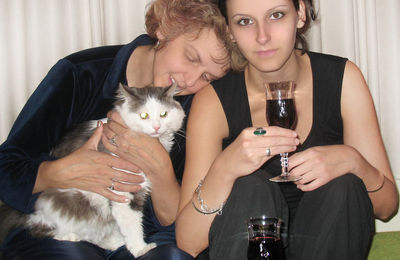 Smiling mother and daughter with cat drinking wine