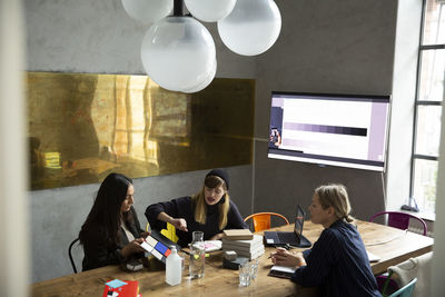 Businesswoman with female colleagues discussing over product in conference room at office