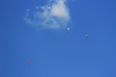 Low angle view of paragliding against blue sky