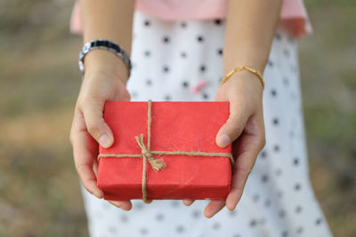 Midsection of woman holding red box