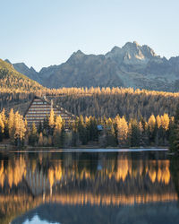 Autumn coloured landscape with a hotel on a bank of a lake with rocky mountains in background