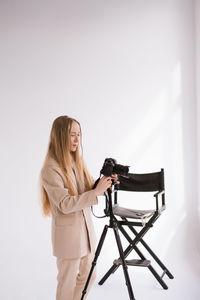 Portrait of young woman sitting on table against white background