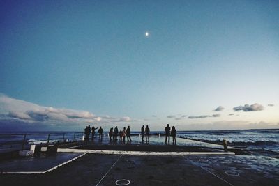 People on pier against sky at dusk