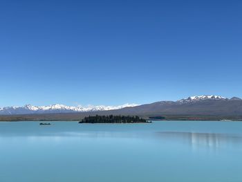 Scenic view of lake and mountains against clear blue sky