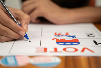 Close-up of hand holding paper with text on table