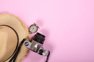 Close-up of clock on table against pink background