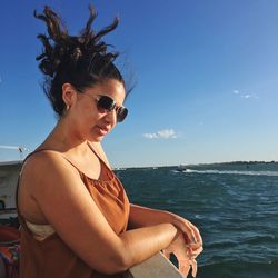 Side view of woman looking away while standing in boat against sky