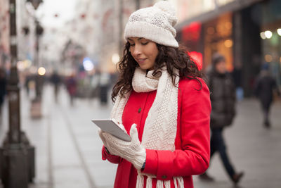 Portrait of smiling young woman standing in city during winter