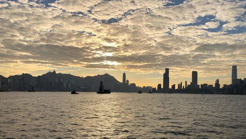 Scenic view of sea by buildings against sky during sunset