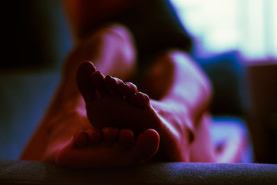 Low section of man relaxing on bed at home