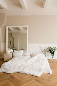 A cozy bed on the floor, a large mirror in a classic modern bedroom. interior of the house