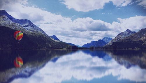 Scenic view of lake and mountains against cloudy sky