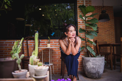 Young woman standing by potted plant on table