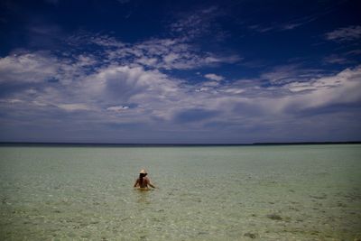 Rear view of young woman swimming on beach