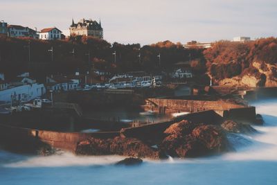 Buildings by sea against sky at sunset