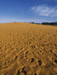 Footprints on sand at beach against sky