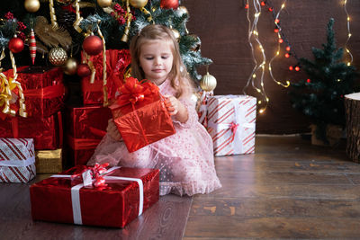 Cute girl holding christmas gift at home