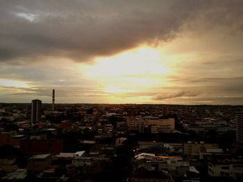 Cityscape against cloudy sky at sunset