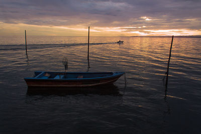 Sailboats moored on sea against sky during sunset