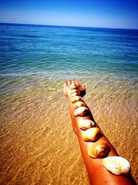 Low section of man relaxing on sand at beach