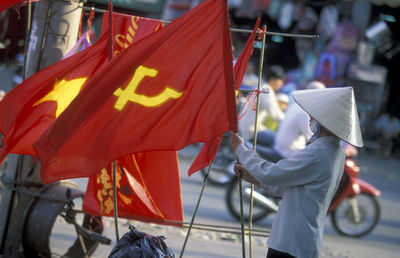 Side view of person holding red flag while standing on street