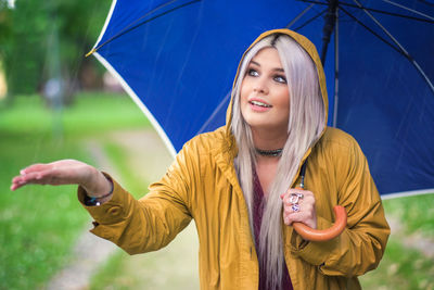 Young woman with blue umbrella enjoying rain on field