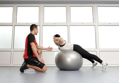 Personal trainer helping client at gym in the uk