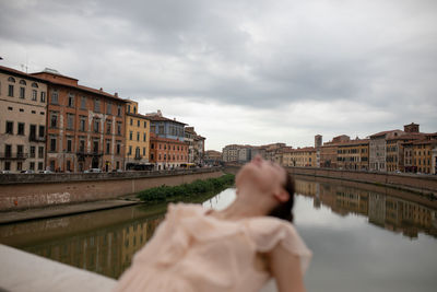 Woman bending over backwards on bridge in city