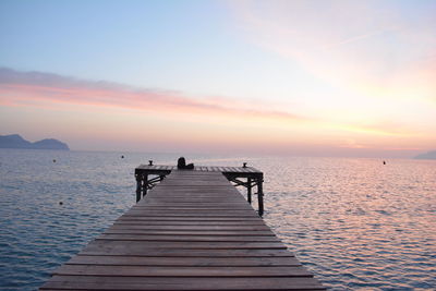 Pier over sea against sky during sunset