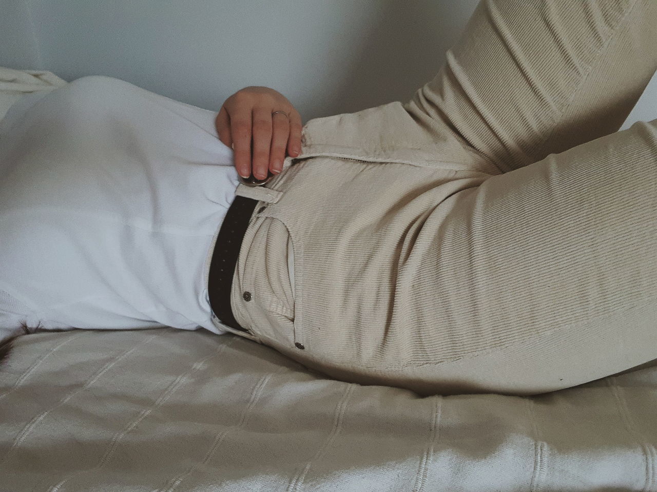 LOW SECTION OF MAN RELAXING ON BED