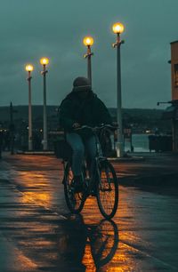 Front view of a girl riding bicycle on street at night