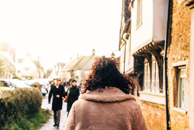 Rear view of people walking in front of buildings